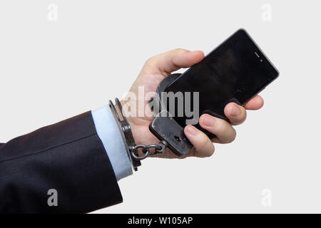 Ein Mann in einem Anzug wird an ein Smartphone gefesselt, das er in der Hand hält. Konzept: Gadget-sucht, letzter Anruf. Stockfoto