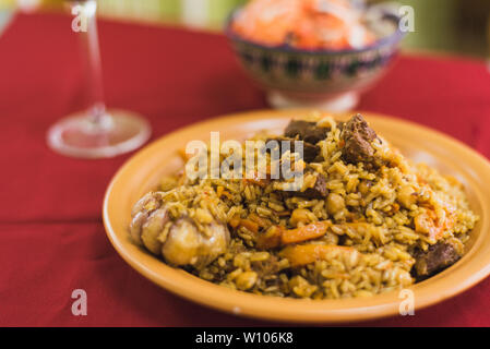 Pilav mit roten Wein in ein Glas und eine Salat von Tomaten und Zwiebeln. Orientalische Schale mit Reis und Fleisch auf dem östlichen Platte. Stockfoto