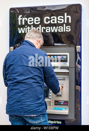 Reifer Mann Geld Abheben aus Geldautomaten Automated Teller Loch in der Wand, Schottland, UK Stockfoto