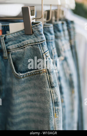 Jeans auf Kleiderbügeln hängen im Store. Vertikale Foto Stockfoto