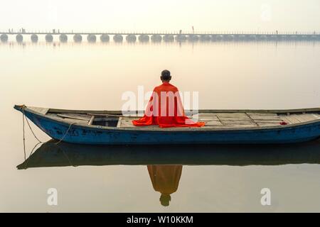 Sadhu mit rotem Schal auf einer Bootsfahrt auf dem Ganges bei Sonnenaufgang, Allahabad Kumbh Mela, der weltweit größte religiöse Versammlung, Uttar Pradesh, Indien Stockfoto