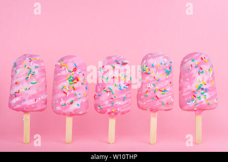 Lustige kreative Konzept von instabilen Ständigen popsicle Streuseln bedeckt auf rosa Hintergrund, kopieren Raum Stockfoto
