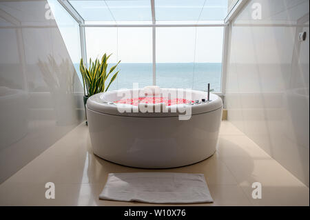 Pattaya, Thailand - 26. Mai 2019: Luxus Whirlpool Badewanne mit bunten Blumen in Wasser mit Himmel und Meer Blick Stockfoto