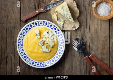 Italienische Küche Polenta mit Käse Gorgonzola auf hölzernen Tisch. Ansicht von oben. Stockfoto