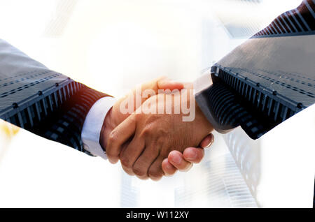 Partnerschaft. Double Exposure Bild von Investor mann Handshake mit Partner für erfolgreiche Tagung befassen sich mit bei Sonnenaufgang und Stadtbild Stockfoto
