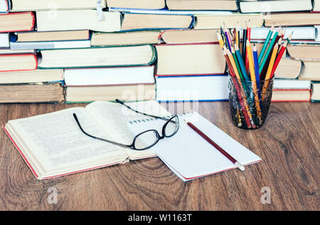 Stapel Bücher, gebundene Bücher auf Holztisch, offenes Buch, Notebook und Gläser, kopieren Platz für Text Stockfoto