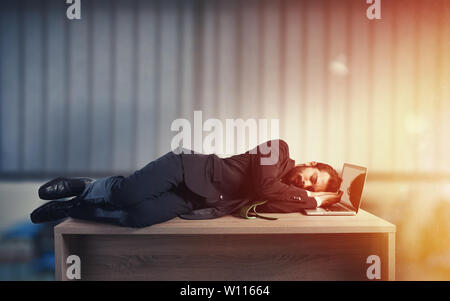 Geschäftsmann Schlaf über einen Schreibtisch wegen Überlastung Stockfoto