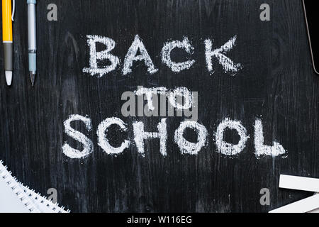 Zurück zu Schule Phrase auf schwarzem Holz Hintergrund geschrieben. Neue Semester, Bildung Konzept: Flach der Schule Zubehör und handschriftlichen Worte mit ch Stockfoto