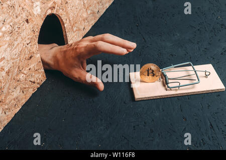Mann Hand reicht für die Münze bitcoin, die in einer Mausefalle. Konzept, Finanzen und cryptocurrency. Stockfoto