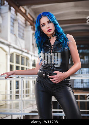 Cooler Rock Girl (informelle Modell) mit blauen Haaren, der in der schwarzen Leder Hose und Weste gekleidet Stockfoto
