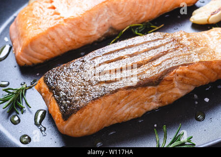 Gegrillter Lachs Steaks in einer Pfanne mit Knoblauch und Rosmarin. Gesunde Ernährung Konzept. Stockfoto