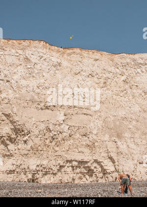 Birling Gap, Eastbourne, East Sussex, UK 28. Juni 2019. Schauen Sie vorsichtig. Spitze der Klippe, Füße über den Rand. Einige scheinen sich der Zerbrechlichkeit und Unterschneidung entlang der Kreidefelsen nicht bewusst zu sein. Felsstürze treten häufig auf. Es ist nicht sicher am Rand. Bitte schützen Sie sich. Stockfoto