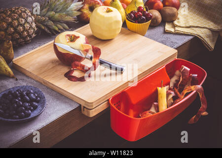 Schneidbrett mit roten Abfallbehälter mit frischen Früchten Hintergrund. Gesunde Ernährung vegane Rohkost Konzept. Stockfoto