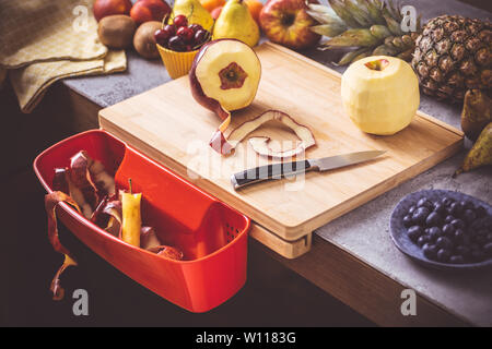 Schneidbrett mit roten Abfallbehälter mit frischen Früchten Hintergrund. Gesunde Ernährung vegane Rohkost Konzept. Stockfoto