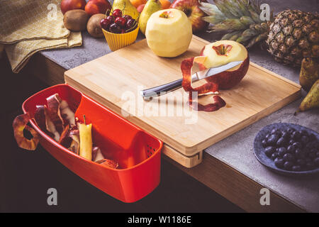 Schneidbrett mit roten Abfallbehälter mit frischen Früchten Hintergrund. Gesunde Ernährung vegane Rohkost Konzept. Stockfoto