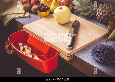 Schneidbrett mit roten Abfallbehälter mit frischen Früchten Hintergrund. Gesunde Ernährung vegane Rohkost Konzept. Stockfoto