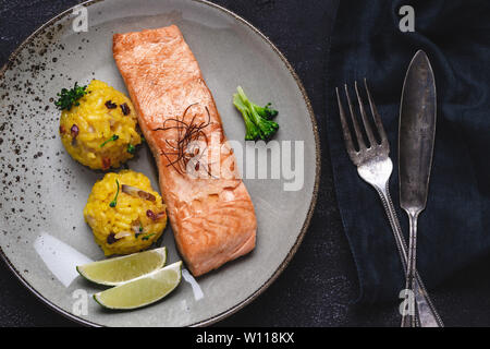 Gegrilltes Lachssteak mit gelben Risotto und Kalk auf Stein. Gesunde Ernährung Konzept. Stockfoto