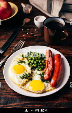 Frühstück mit Spiegelei, Würstchen und grünen Erbsen auf weiße Platte Stockfoto