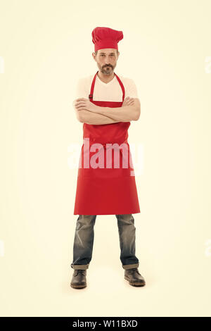 Für seine Küche bekannt. Reife bärtige Mann in Chef hat und Schürze. Senior Kochen mit Bart und Schnurrbart tragen Latzschürze. Reifen chief Cook in rot Kochschürze. Home Kochen. Stockfoto