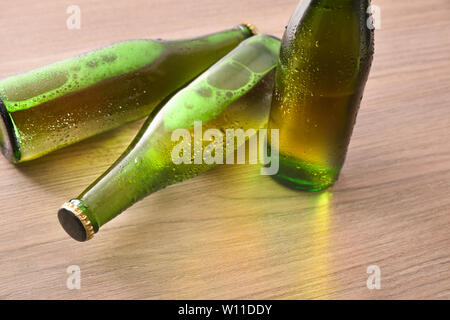 Drei grüne Flaschen mit alkoholischen Getränken auf hölzernen Tisch erhöht. Horizontale Komposition. Erhöhte anzeigen. Stockfoto
