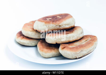 Gebratene Kuchen mit Kartoffeln und Bohnen auf weißem Hintergrund Stockfoto