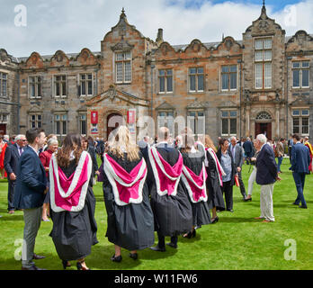 ST ANDREWS UNIVERSITY FIFE SCHOTTLAND St. Salvators College Graduation Day IM SOMMER ABSOLVENTEN IN bunten Gewändern auf dem Rasen Stockfoto