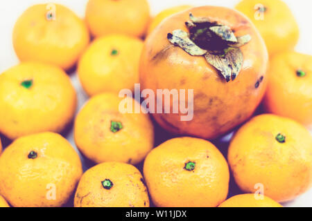 Frische ganze Mandarin orangen Hintergrund mit Kakipflaume, Ansicht von oben Stockfoto