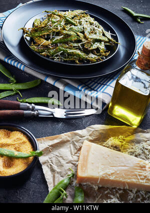 Knusprig gerösteten Parmesan und Polenta panierte Zuckerschoten Pommes auf Teller serviert. Zutaten auf einer konkreten Tabelle, vertikale Ansicht von oben Stockfoto