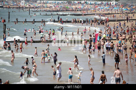 Menschen gehen auf dem Wasser, während Sie die Sonne und warme Wetter am Strand von Bournemouth, Dorset genießen. Stockfoto