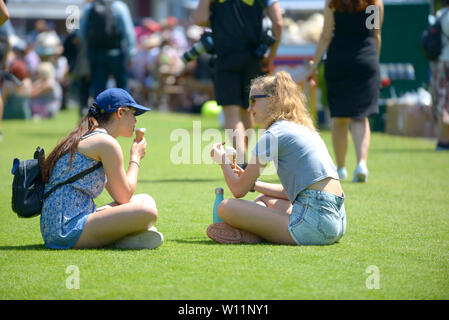 Zwei Mädchen essen Eis, Devonshire Park, Eastbourne, Großbritannien. 29 Juni, 2019. Perfektes Wetter für das Tennis, wenn auch vielleicht ein wenig warm zu spielen - auf die Natur Tal International Tennis Stockfoto