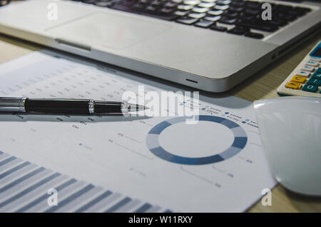 Geschäftliche Dokumente finanzielle Diagramme, statistische Analysen an Schreibtisch mit Computer Laptop. Stockfoto