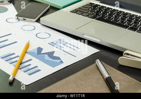 Geschäftliche Dokumente finanzielle Diagramme, statistische Analysen an Schreibtisch mit Computer Laptop. Stockfoto