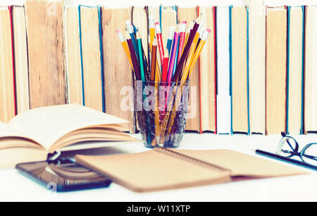 Lehrbuch, Notebook, Smartphone öffnen, Stapel von Büchern Bildung zurück zu Schule Hintergrund, Gläser und Bleistifte in Kunststoff Halter mit Kopie Raum für Tex Stockfoto