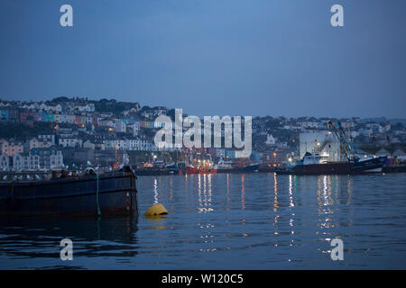 Eine Ansicht von Brixham und die Häuser mit Blick auf den Hafen mit Fischereifahrzeugen im Vordergrund am Abend im Juni. Brixham Devon England UK GB Stockfoto