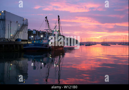 Ein Fischereifahrzeug im Hafen von Brixham bei Sonnenuntergang im Juni. Tourismus und Fischerei sind die wichtigsten Industriezweige in der Stadt. Devon England UK GB Stockfoto