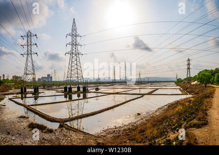 Hohe Spannung Strom Steel Tower in die untergehende Sonne und saltpanes in Mumbai. Pylon und Saltpanes. Stockfoto