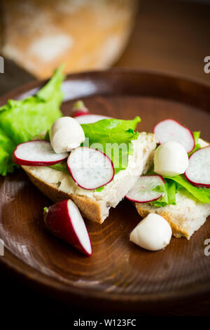 Sandwich mit Käse, Salat und rote Radieschen auf einem Holztisch Stockfoto