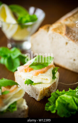 Sandwich mit Käse, Salat und rote Fische auf einem Holztisch Stockfoto