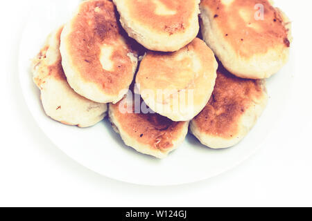 Gebratene Kuchen mit Kartoffeln und Bohnen auf weißem Hintergrund Stockfoto