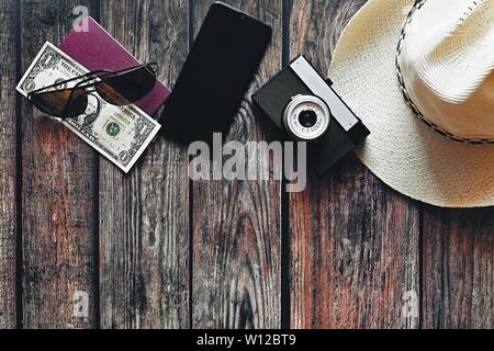 Produkte für Sommerferien: eine Kamera, Reisepass, Smartphone, Geld, Hut, Sonnenbrille. Holz- Hintergrund, Ansicht von oben mit Platz kopieren. Schönen Sommer anhand von quantitativen Simulatio Stockfoto