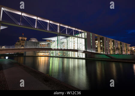 Moderne staatliche Gebäude Paul-Loebe-Haus an der Spree in Berlin in der Dämmerung beleuchtet. Der Reichstag mit Glaskuppel ist im Hintergrund. Stockfoto