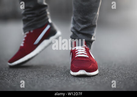 Sport rote Sneakers close-up auf Asphalt. Beine und Schuhe aus der unteren Winkel Stockfoto