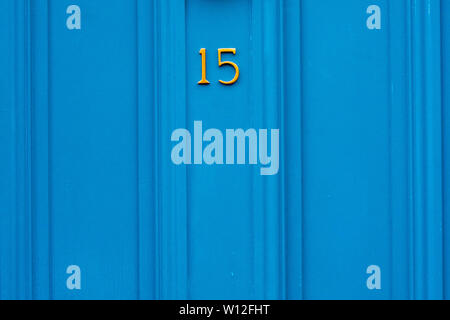Haus Nummer 15, und die 15 in hellen Gelb auf blauem Holz- Vordertür Stockfoto