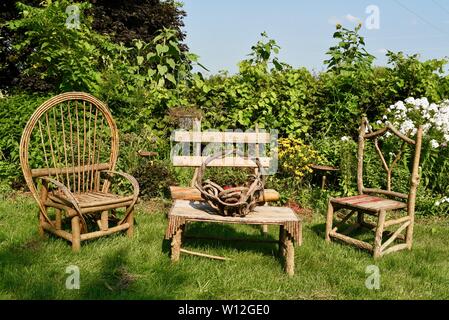 Rustikal, handgefertigt aus Holz Gartenmöbel Stühle und Tisch in einer üppigen Gartenanlage Sitzgelegenheiten im Freien an Squash Blossom Farm, Oronoco, Minnesota, USA. Stockfoto