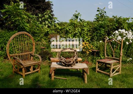 Rustikal, handgefertigt aus Holz Gartenmöbel Stühle und Tisch in einer üppigen Gartenanlage Sitzgelegenheiten im Freien an Squash Blossom Farm, Oronoco, Minnesota, USA. Stockfoto