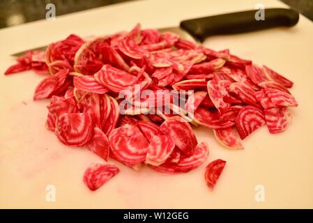 In Scheiben geschnitten, um Frische, helle rote Chioggia Rote Rüben (Rote Beete) auf einem weißen Schneidebrett mit Messer, Wisconsin, USA. Stockfoto