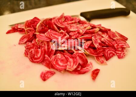 In Scheiben geschnitten, um Frische, helle rote Chioggia Rote Rüben (Rote Beete) auf einem weißen Schneidebrett mit Messer, Wisconsin, USA. Stockfoto