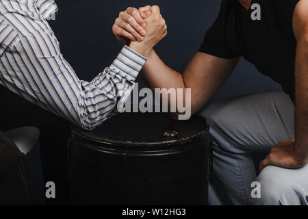 Nahaufnahme von zwei Geschäftsleute in Arm Wrestling konkurrieren auf einem dunkelblauen Hintergrund. Herausforderung, Konkurrenz und Rivalität Konzept - Nahaufnahme der männlichen Freunde Stockfoto