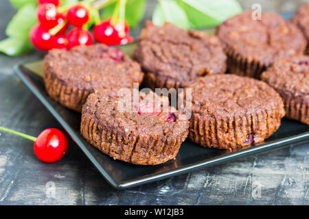 Chocolate Muffin mit frischen Kirschen auf einer Platte Stockfoto