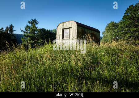 Alte verfallende Website Trailer in einer Sommerwiese im Abendlicht Stockfoto